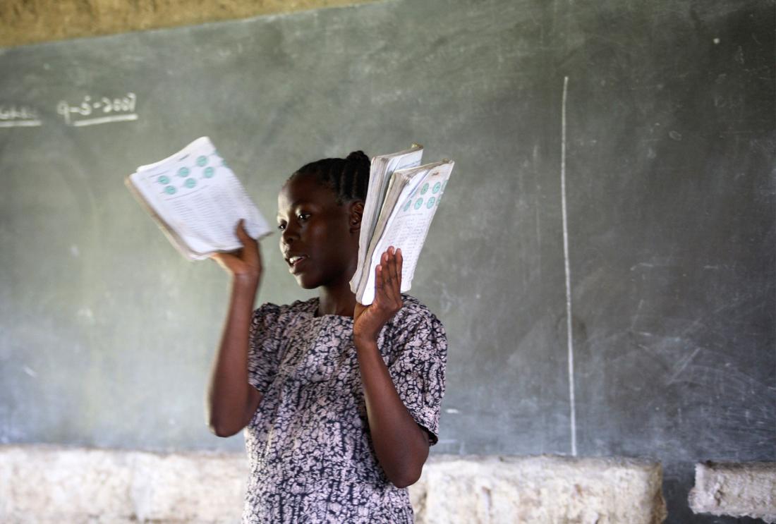 A teacher hands out textbooks to students in Kenya.