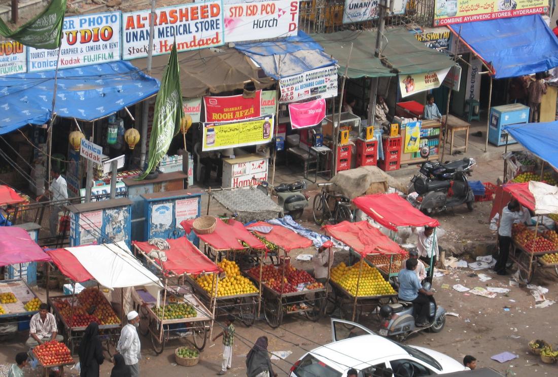Street scene with fruit vendors and electronics stalls in Hyderabad, India