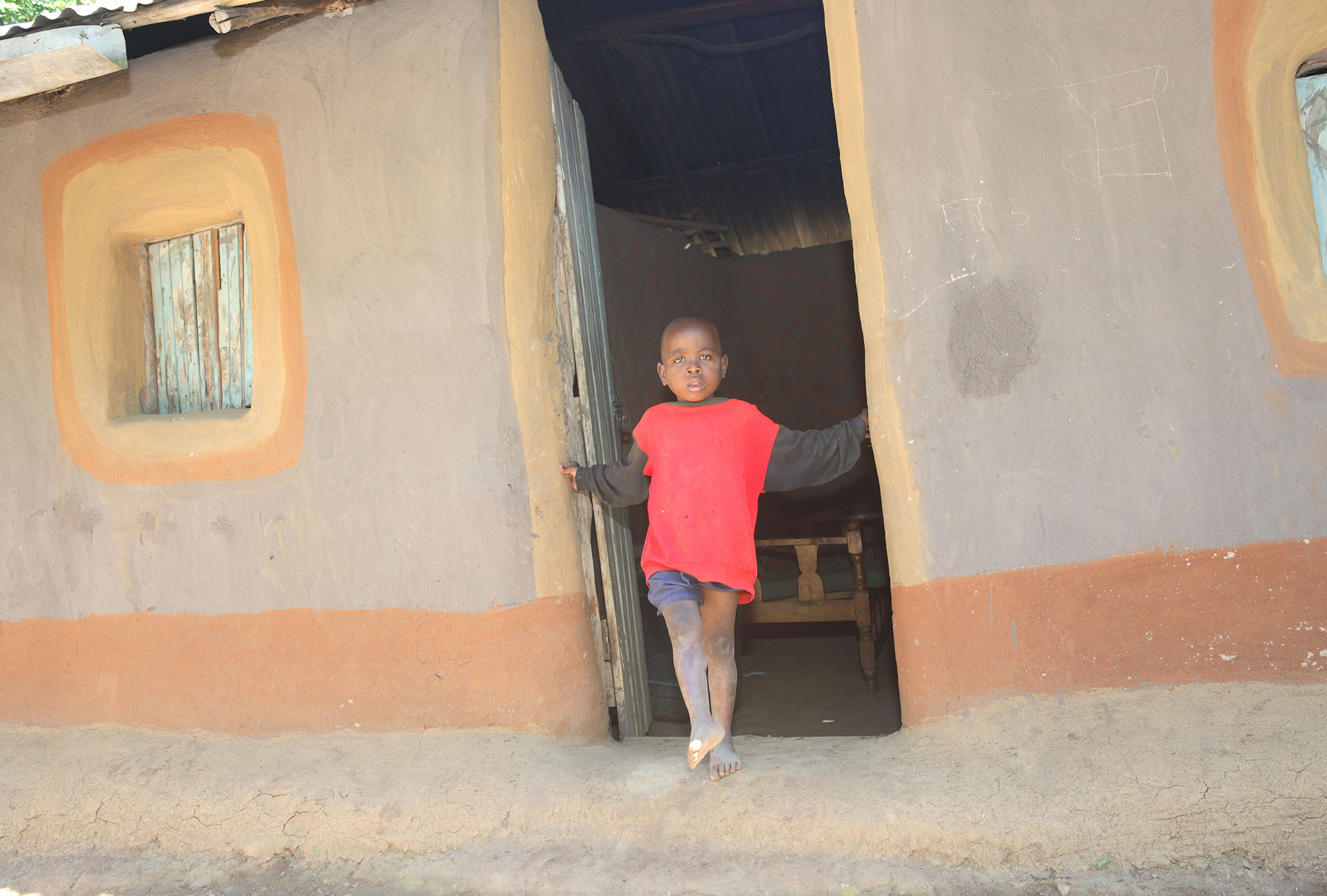 Young boy stands in doorway of house