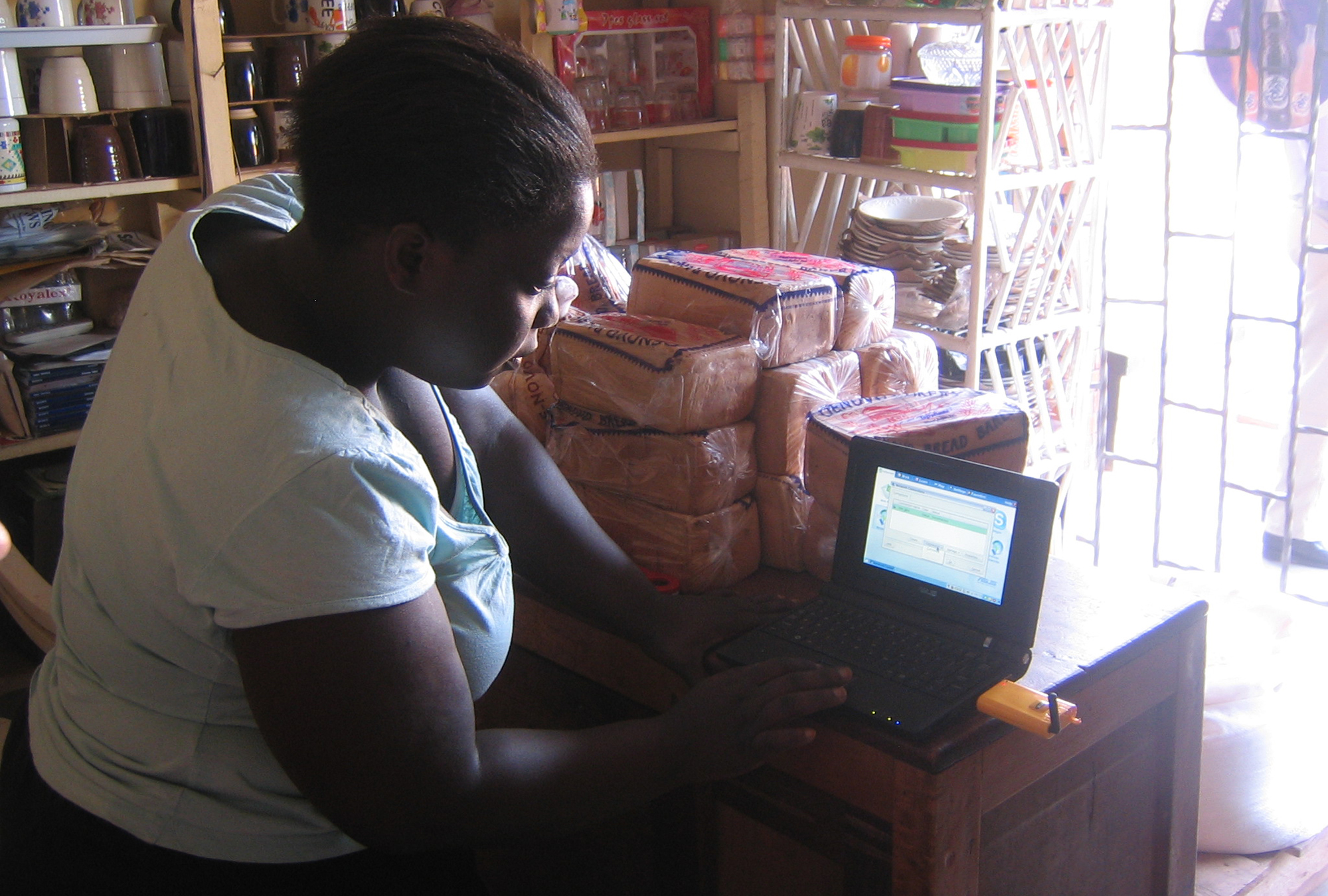 Village phone operator testing her laptop's internet access in rural Uganda
