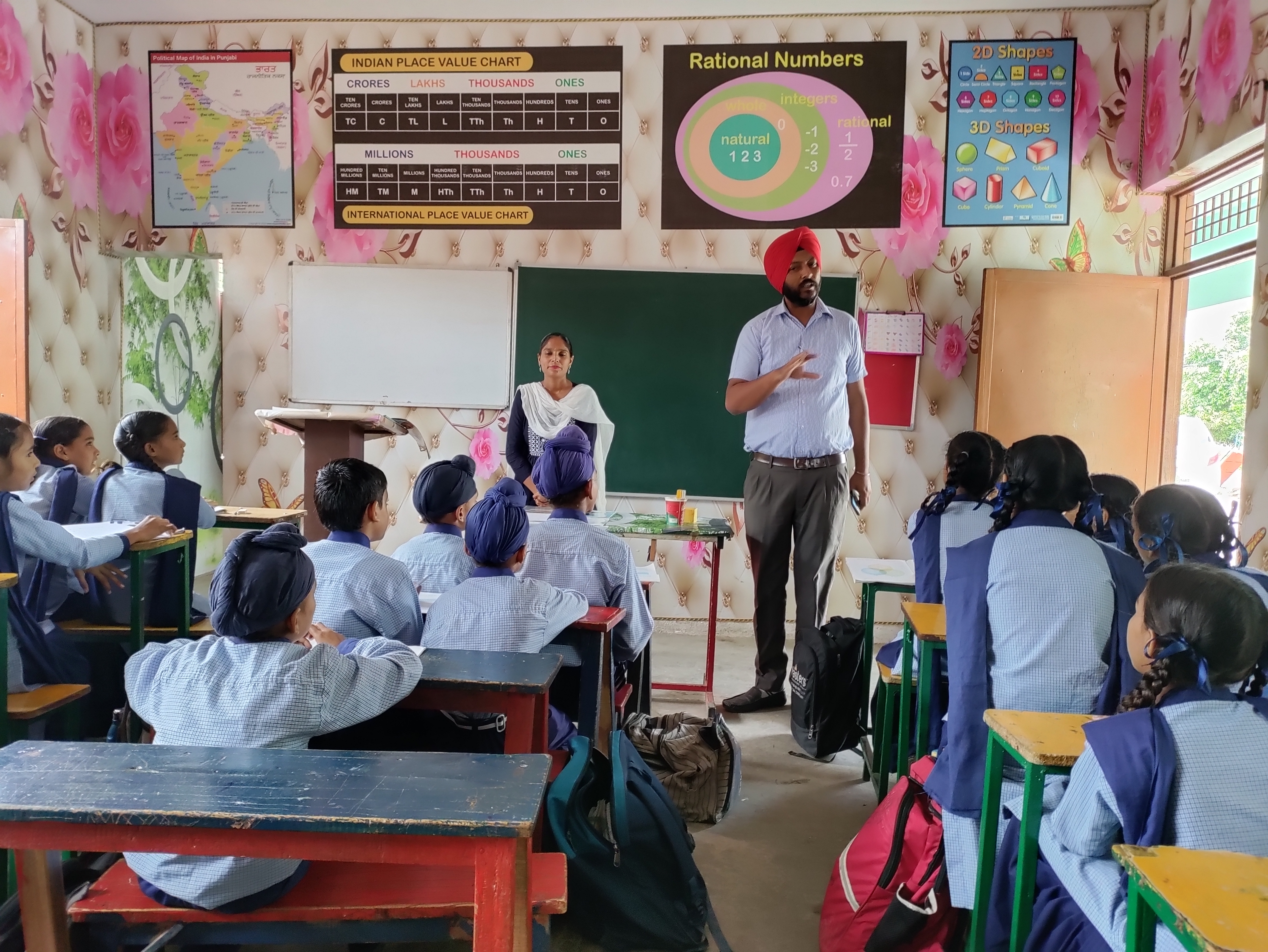 a man and women teaching children in a classroom in india