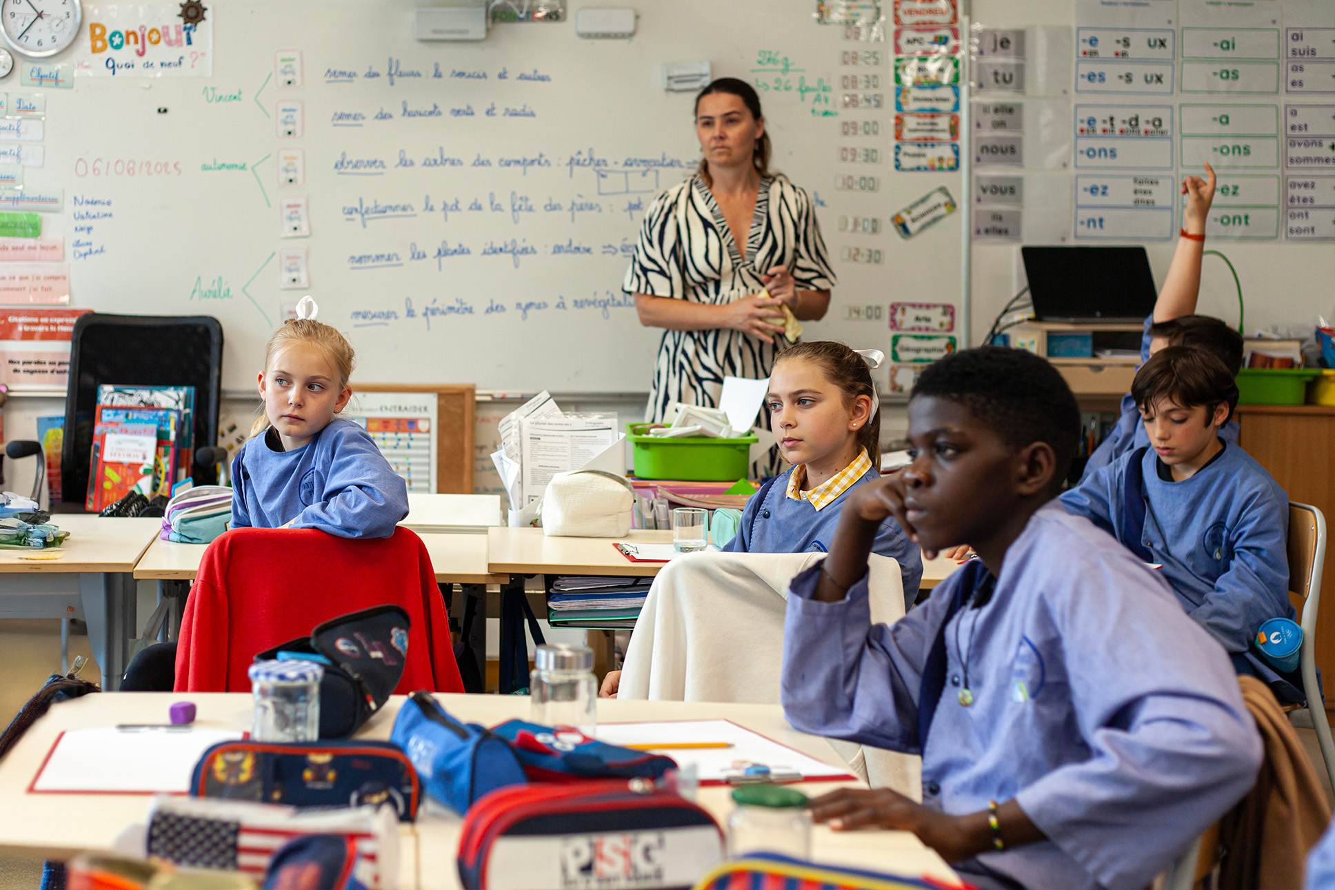 Teacher standing at the back of the classroom with four students at their desks