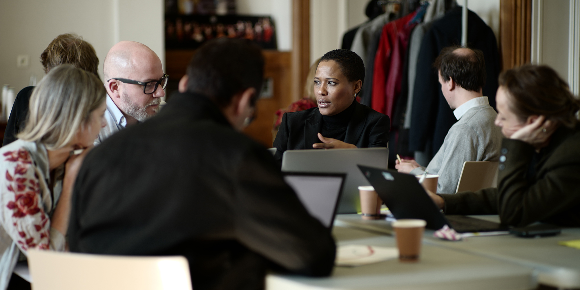 Group of six course participants sitting at a table together discussing a topic