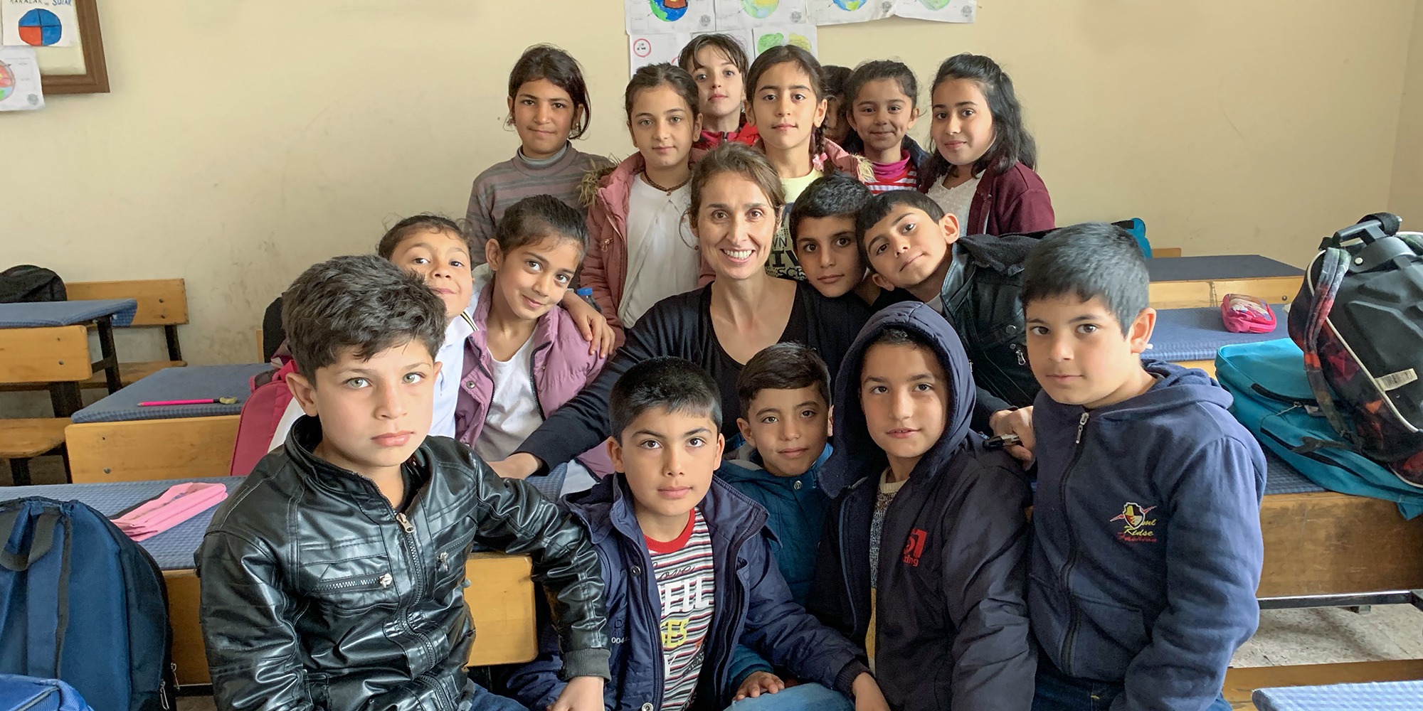 Affiliated professor Sule Alan in a classroom posing with students at their desks