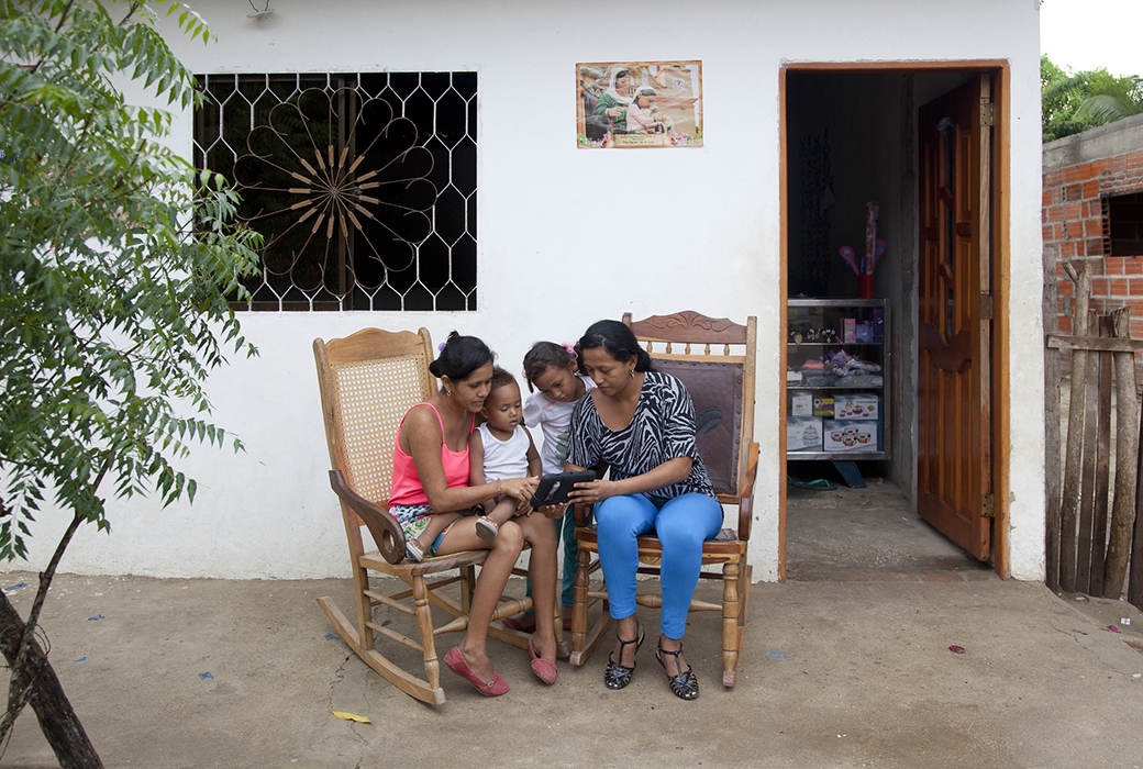 Two women reading on a tablet to a young children