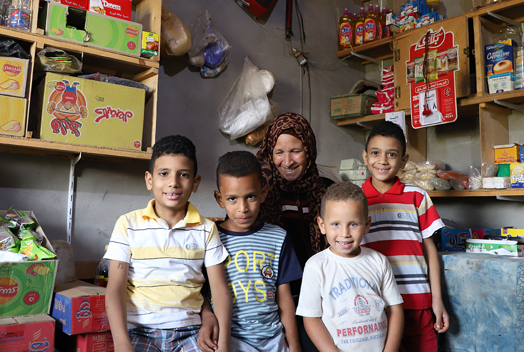 Smiling woman standing with her four boys in her storefront