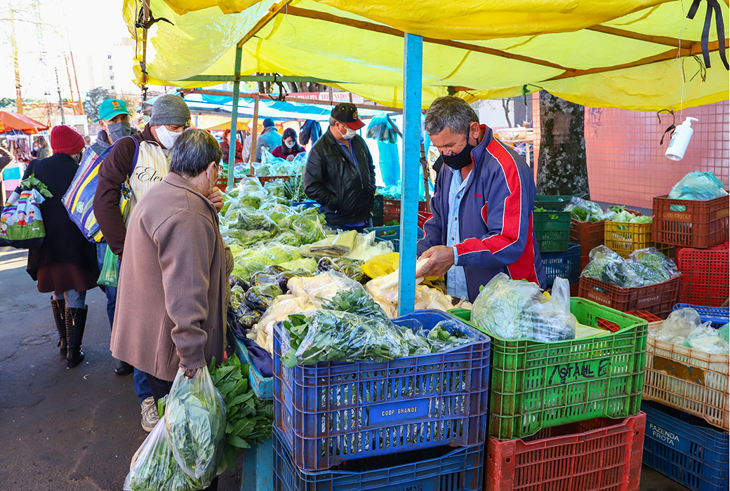 Man stands in market purchasing vegetables from a vendor
