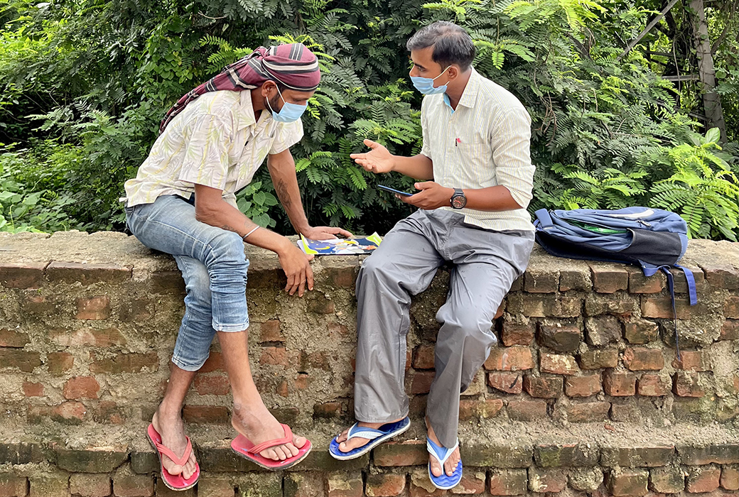 Two men sitting on together talking; a survey is taking place