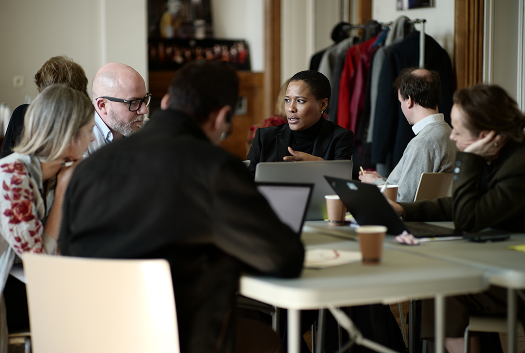 Group of six course participants sitting at a table together discussing a topic