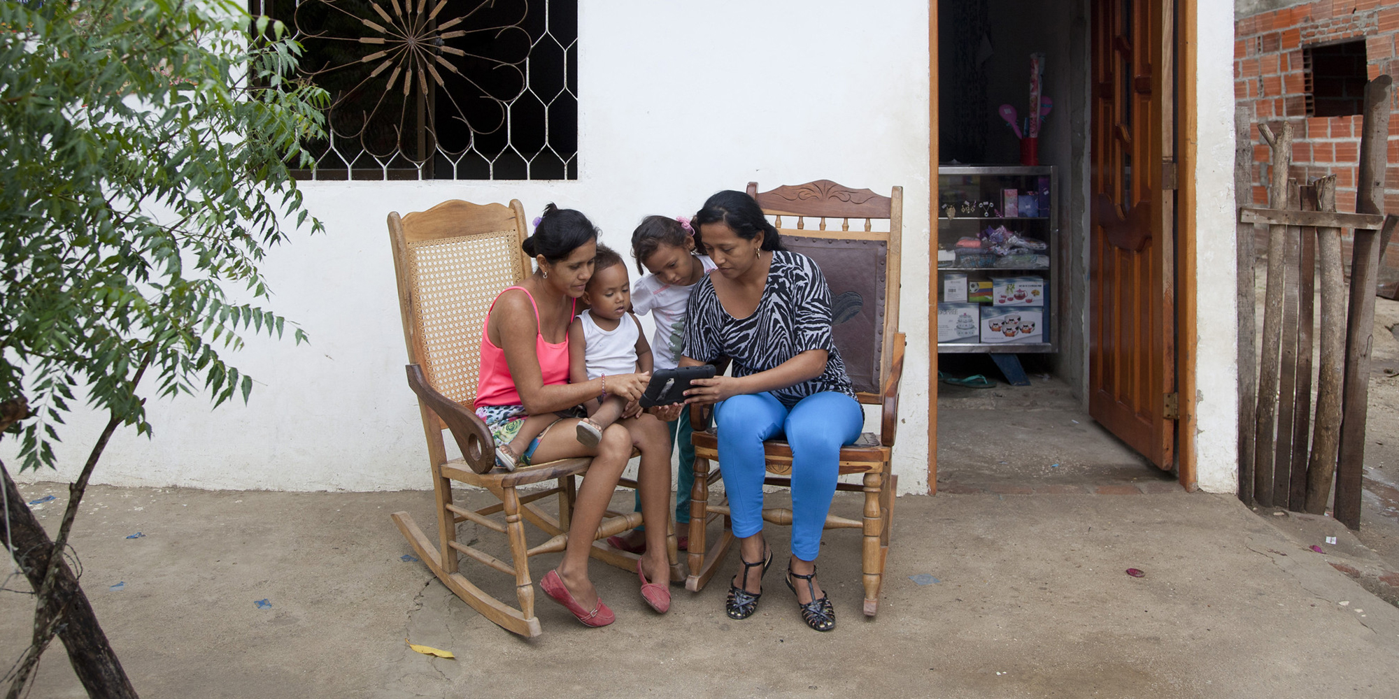 Two women reading on a tablet to a young children