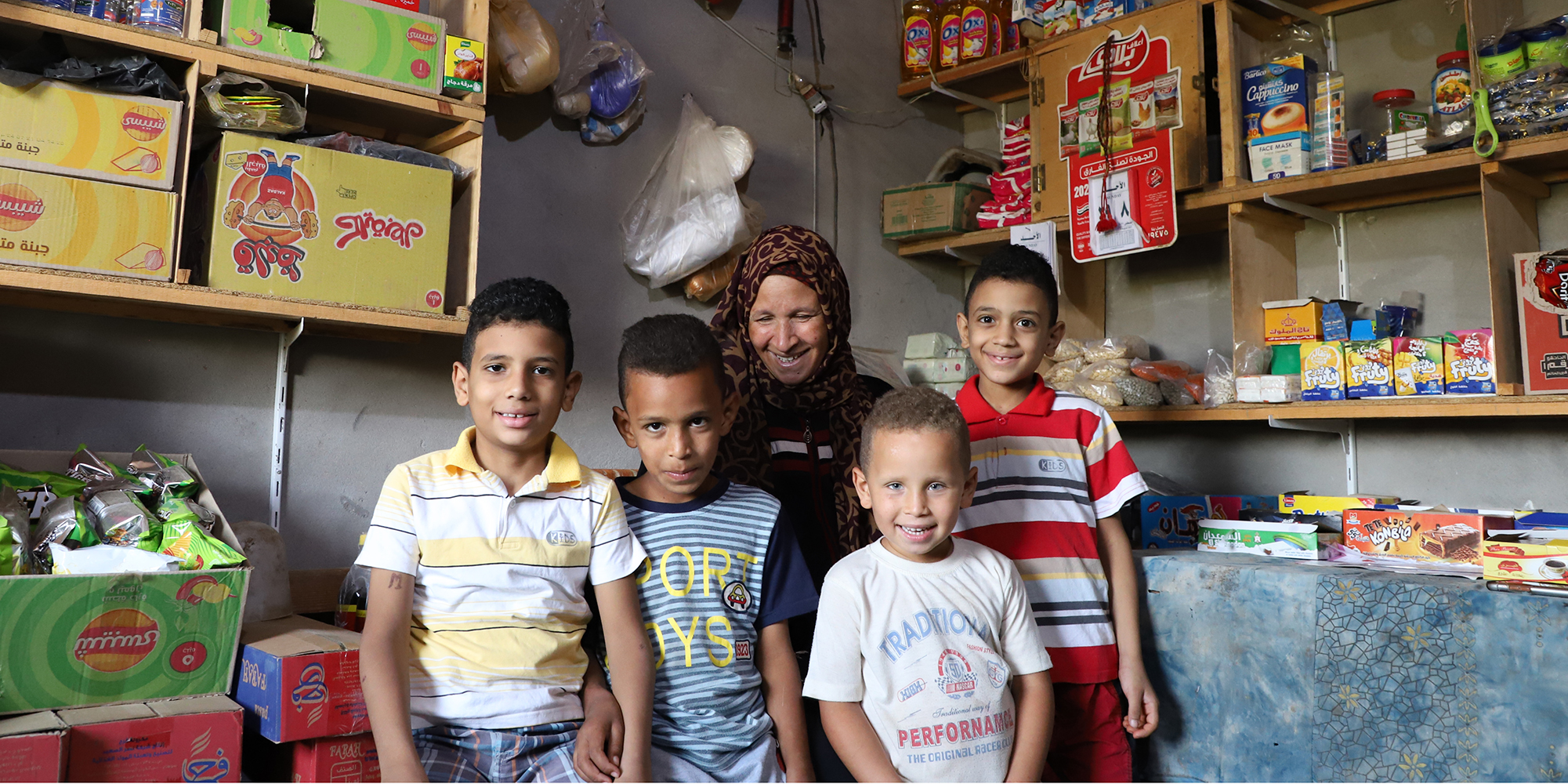 Smiling woman standing with her four boys in her storefront