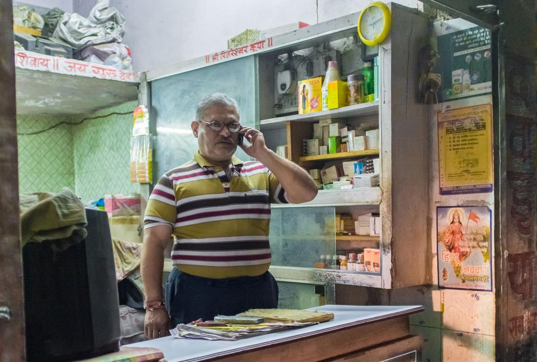 Man stands in small shop talking on phone