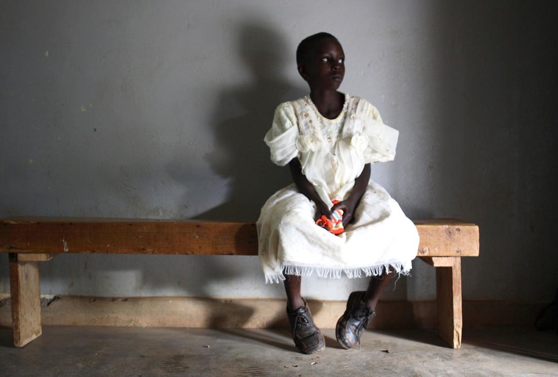 A young girl waits in a health center in Uganda.