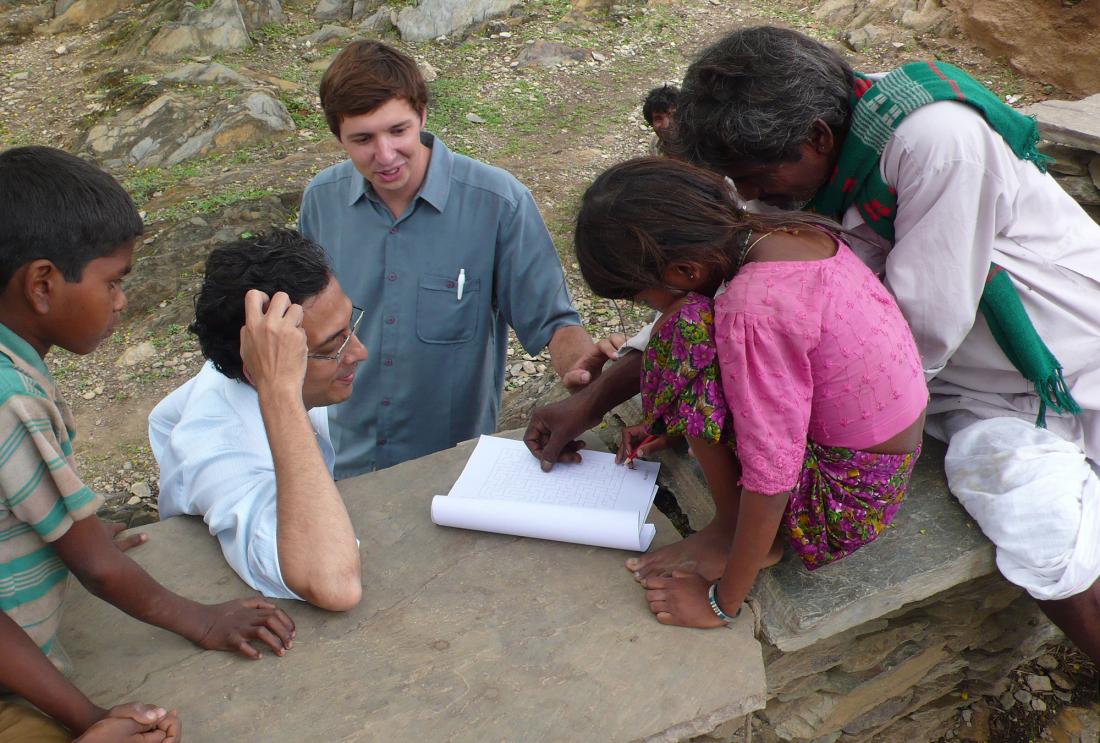 J-PAL staff help a young girl solve a maze exercise in India.