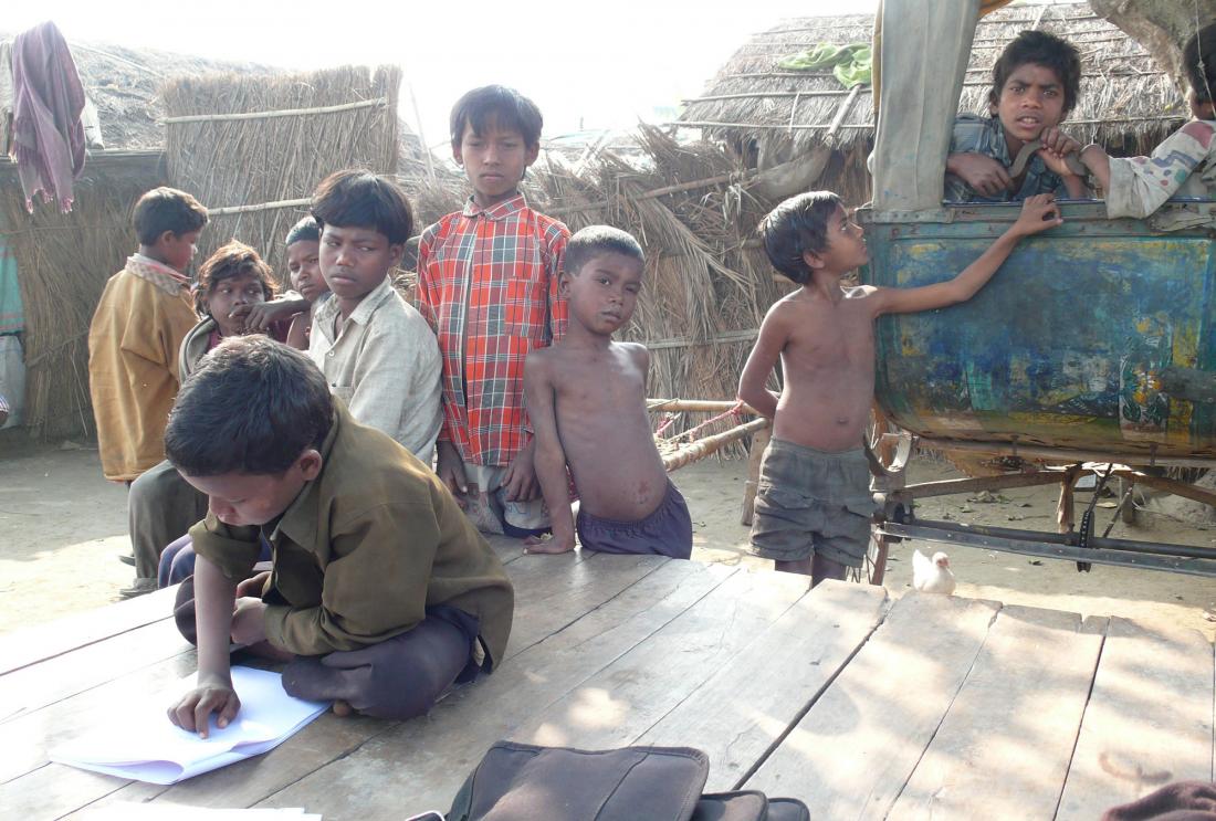 A young child reads among onlookers in India.