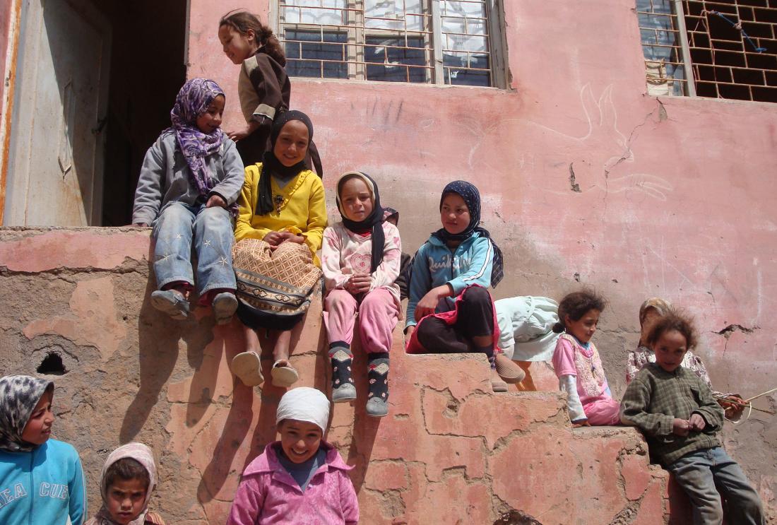 Group of children in headscarves wait on stairs outside Moroccan school