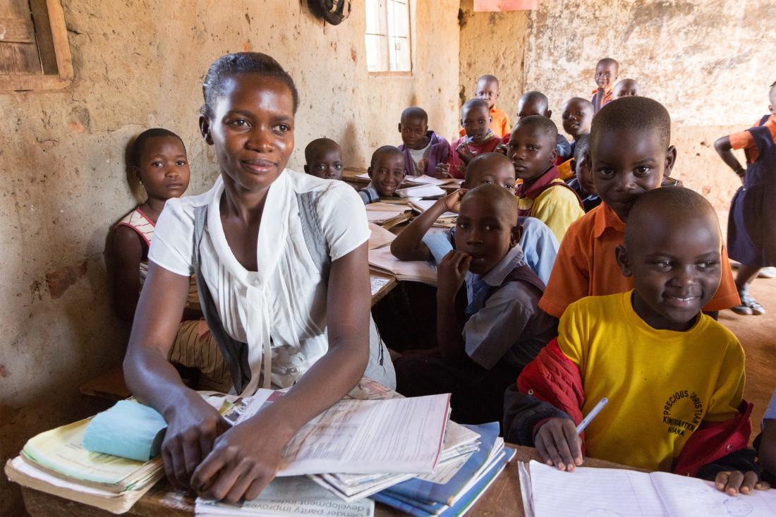 Primary school teacher and students in a classroom in Uganda.