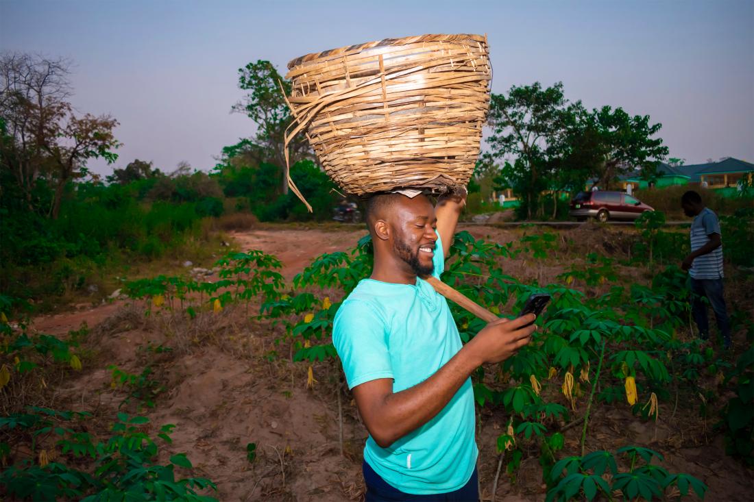 farmer holding a basket on his head and a cell phone in his hand