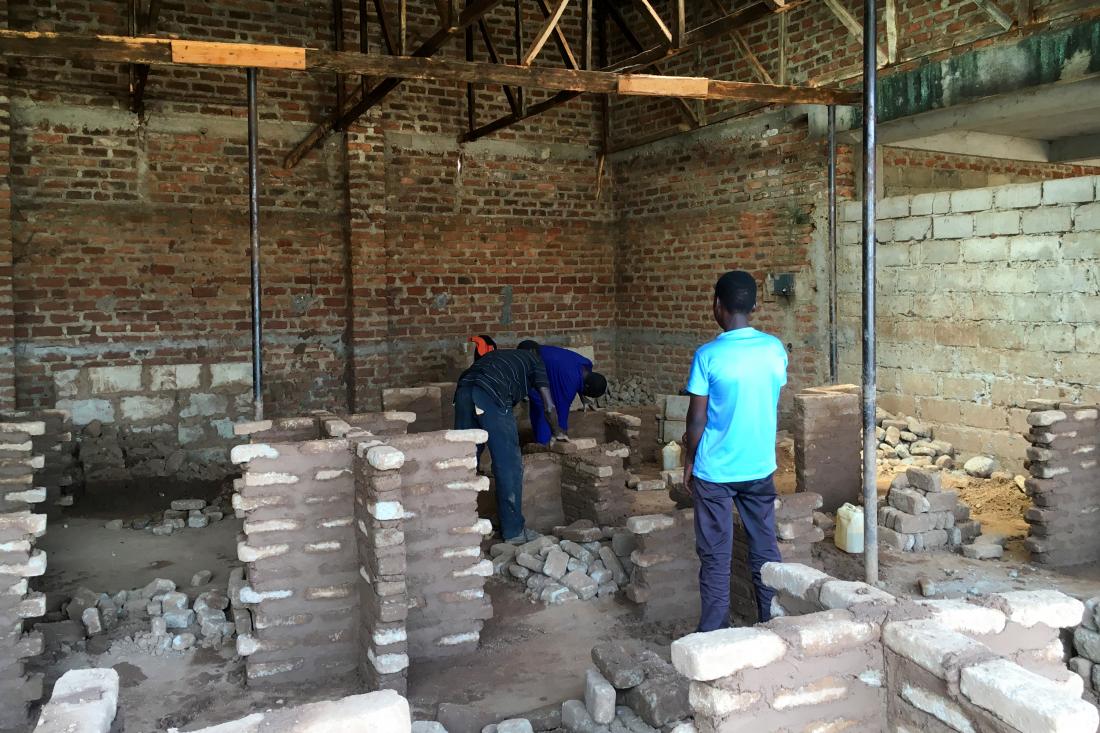 Three young men work on a construction site laying bricks.