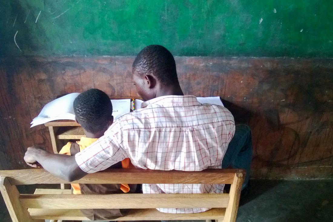 teacher with arm around student reading a book