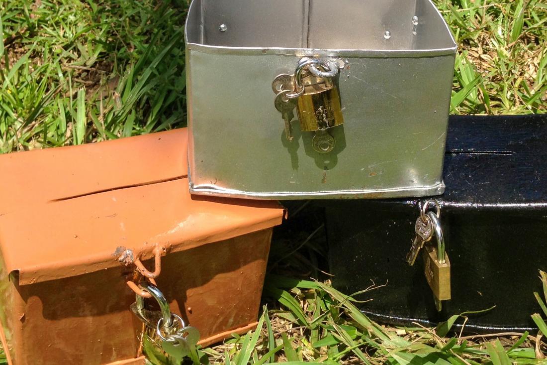 Three lockboxes stacked on the ground.