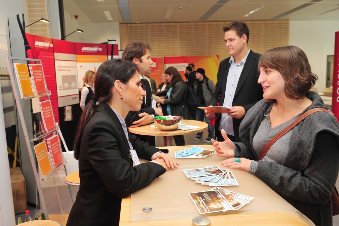 Jobs seekers talk with employers at a job fair table.