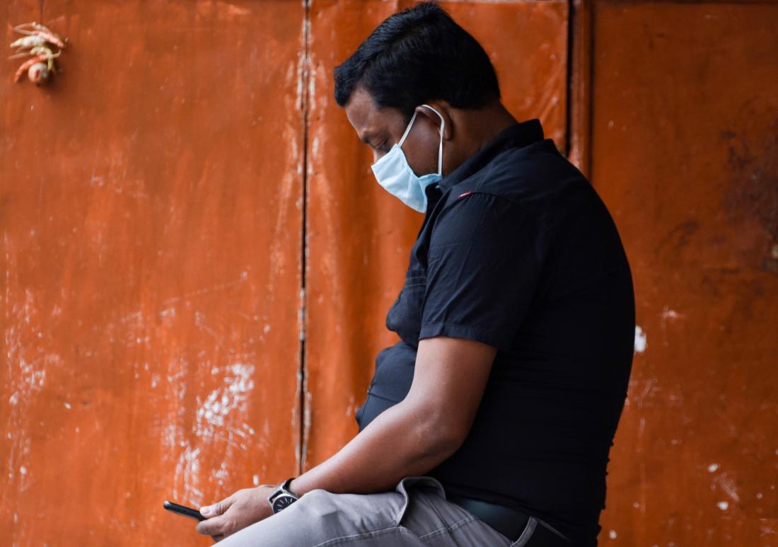 man wearing face mask looking at cell phone