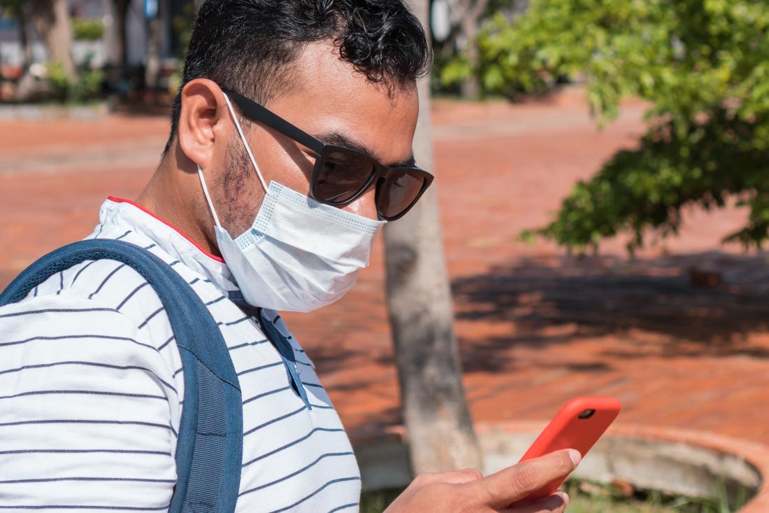 man wearing surgical mask using cell phone