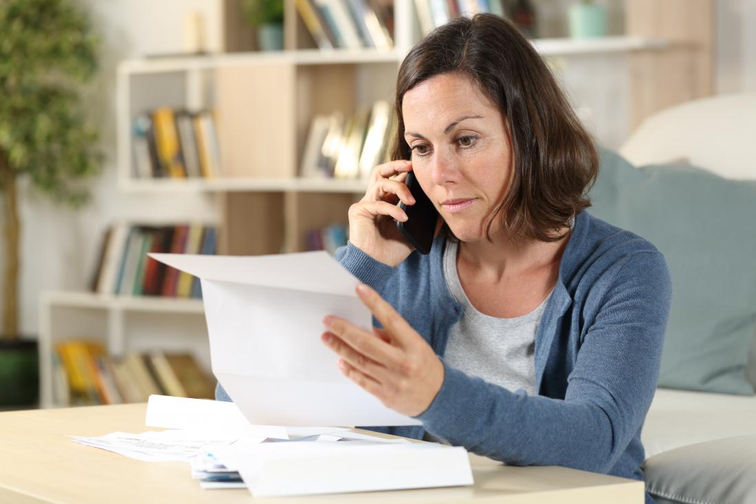 woman reading letter and talking on a cell phone