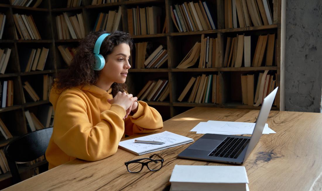 student wearing headphones sitting in front of a laptop
