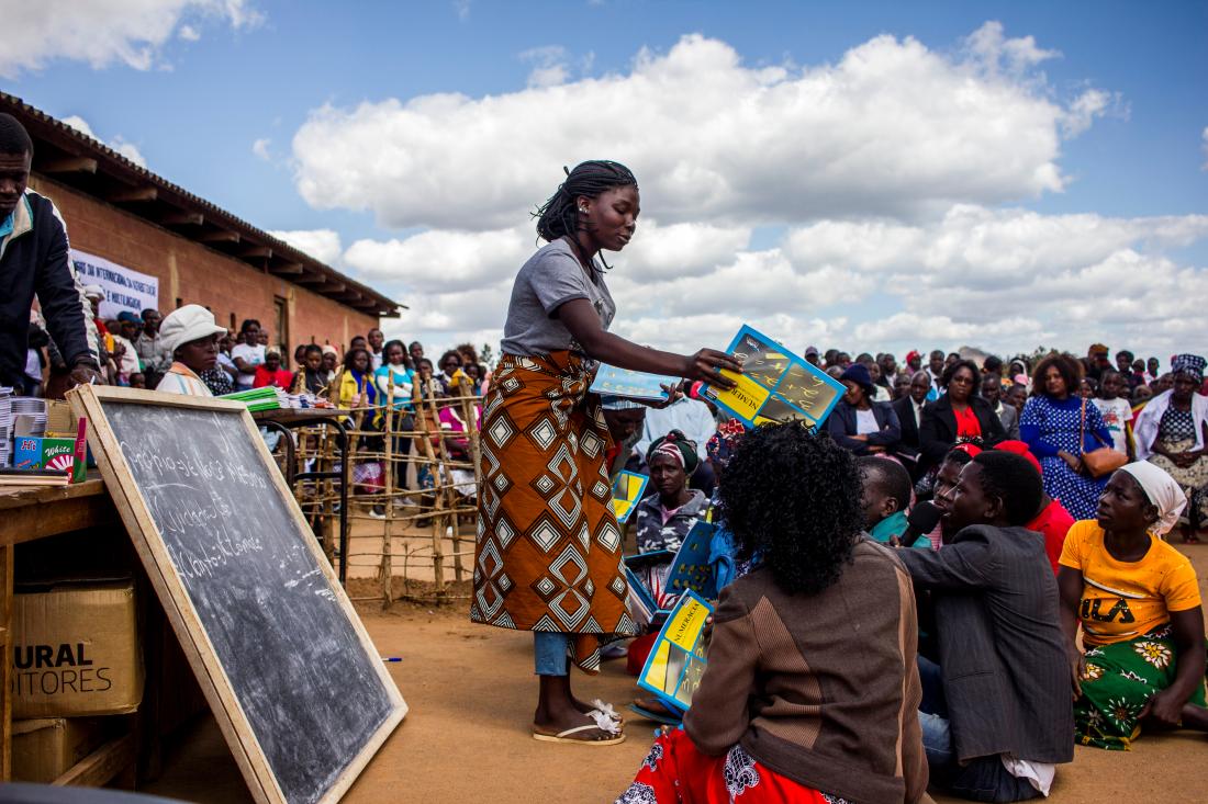 A woman hands out books to adult learners