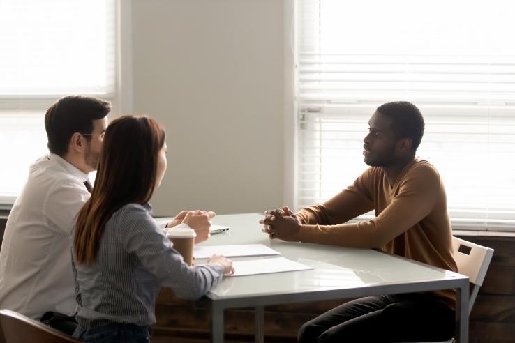 Three people sit facing each other at a table.