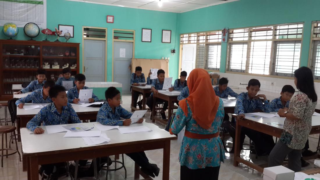 An instructor reads to students in a classroom 