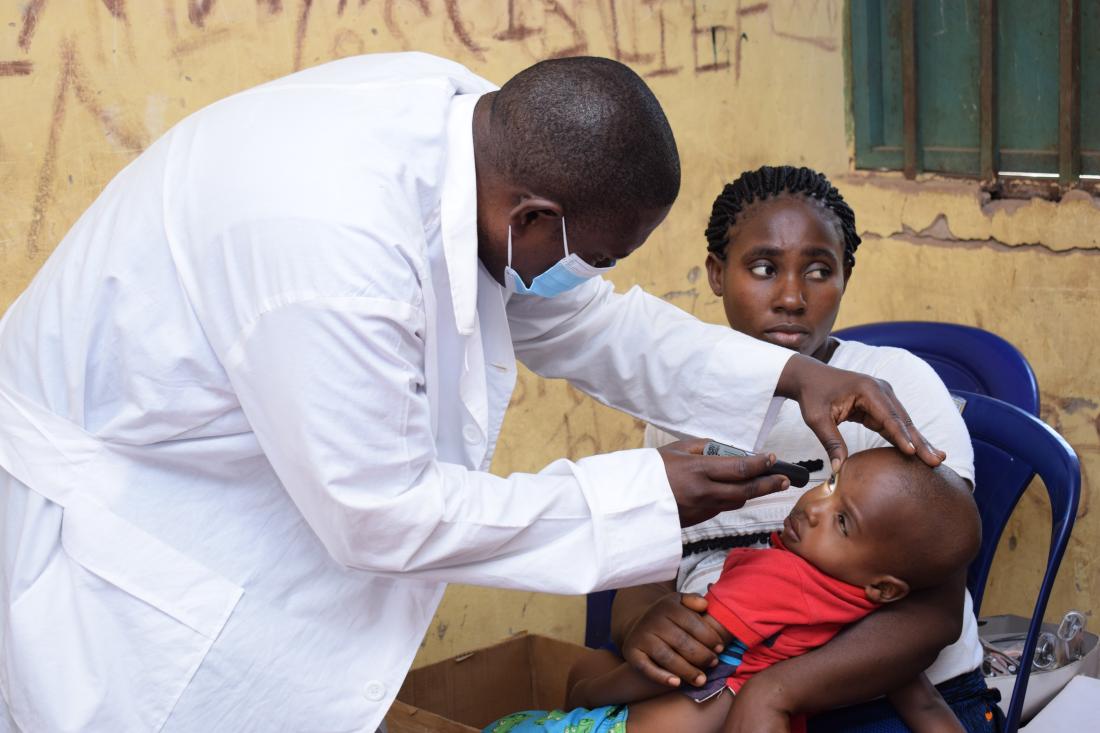 A doctor examines the eyes of a child held by his mother in rural Nigeria.
