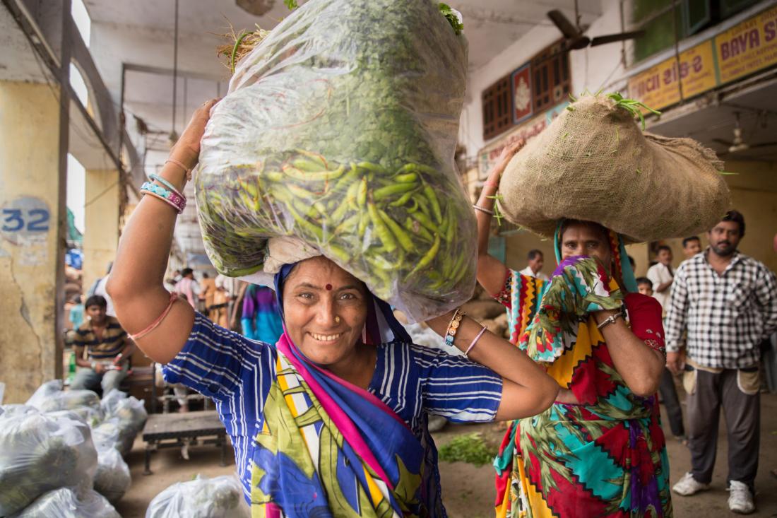 Two working women at a market place with men in the background