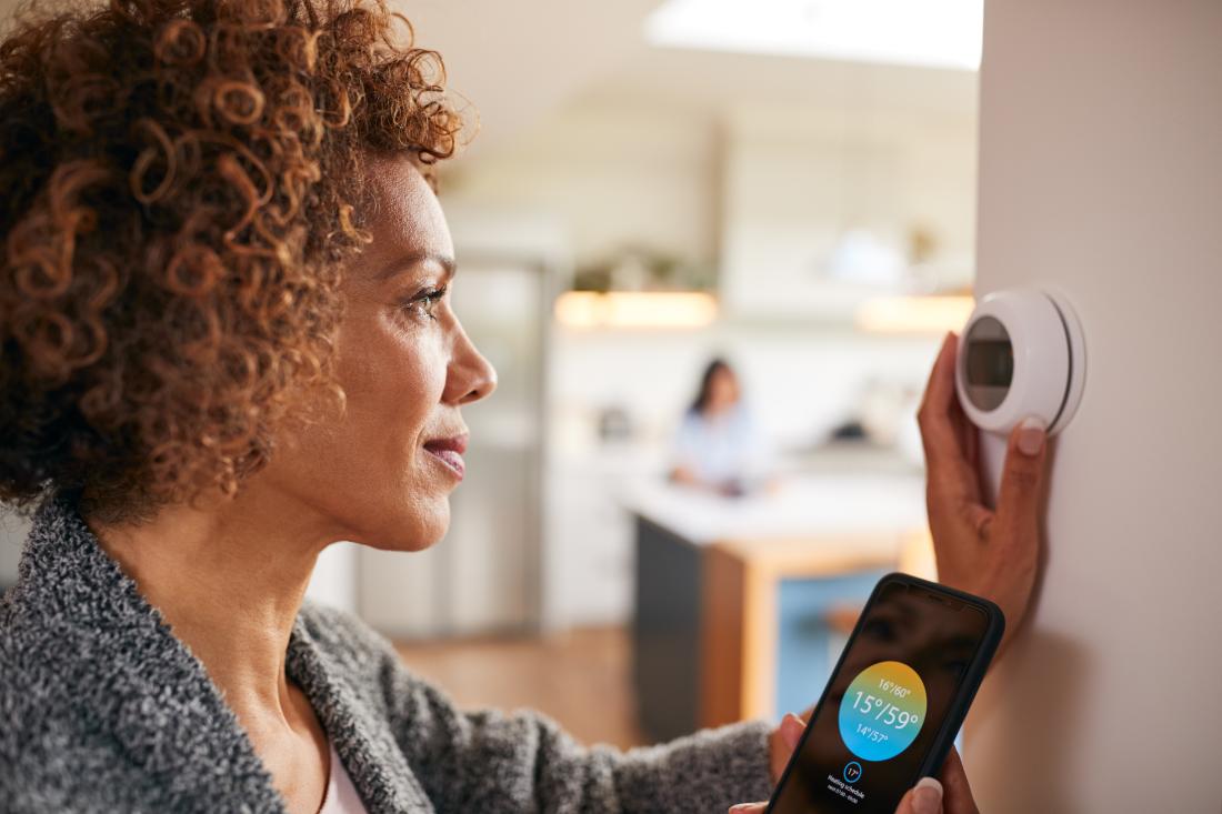 Women using app to control thermostat.