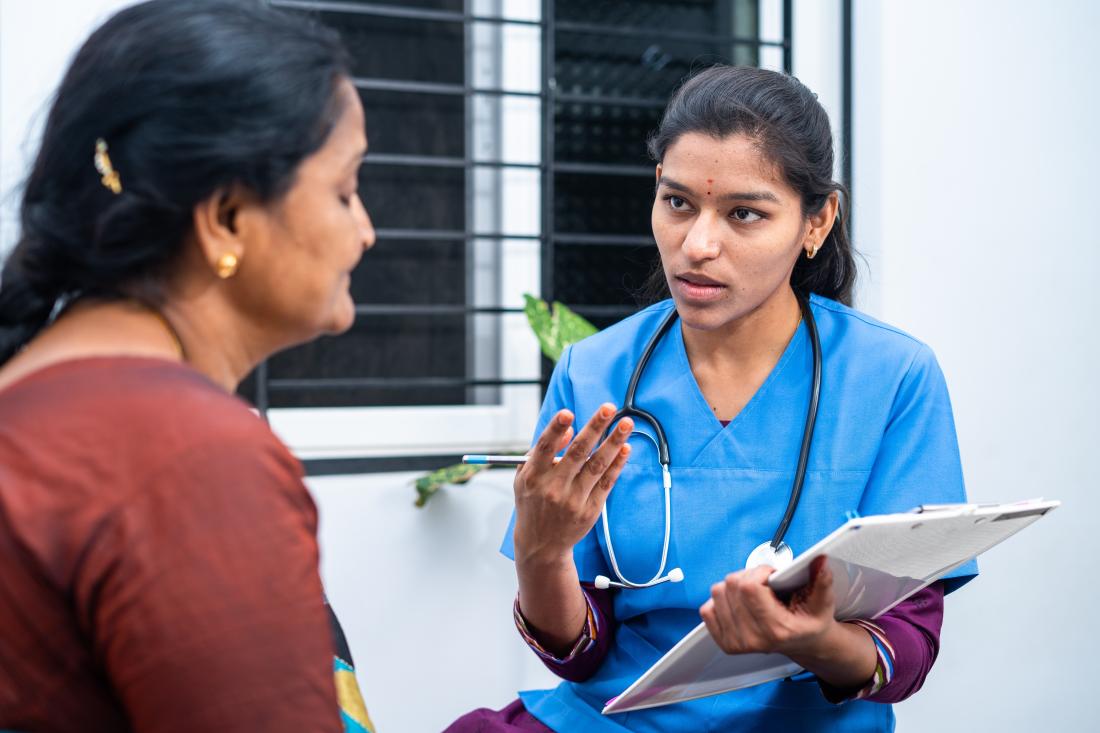 A female nurse examines a female patient at a clinic in India.