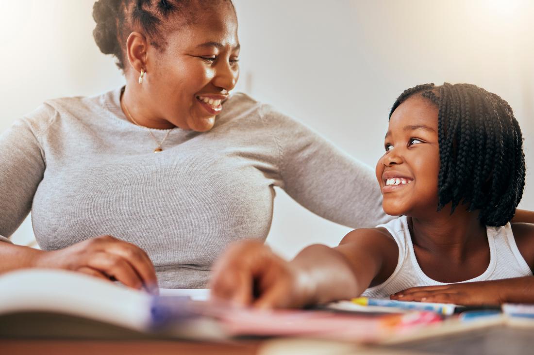 A Kenyan mother and her child smile as they learn from books