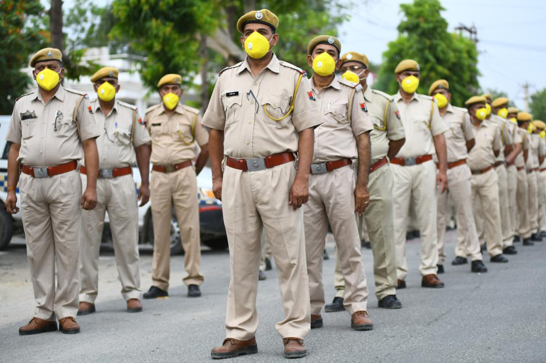 Image of Rajasthan police in uniforms and with masks walking in two rows.