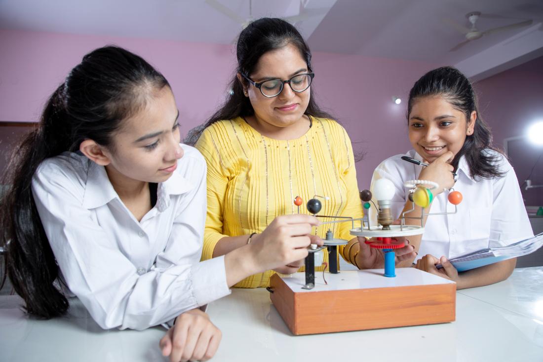 A science teacher helps two students