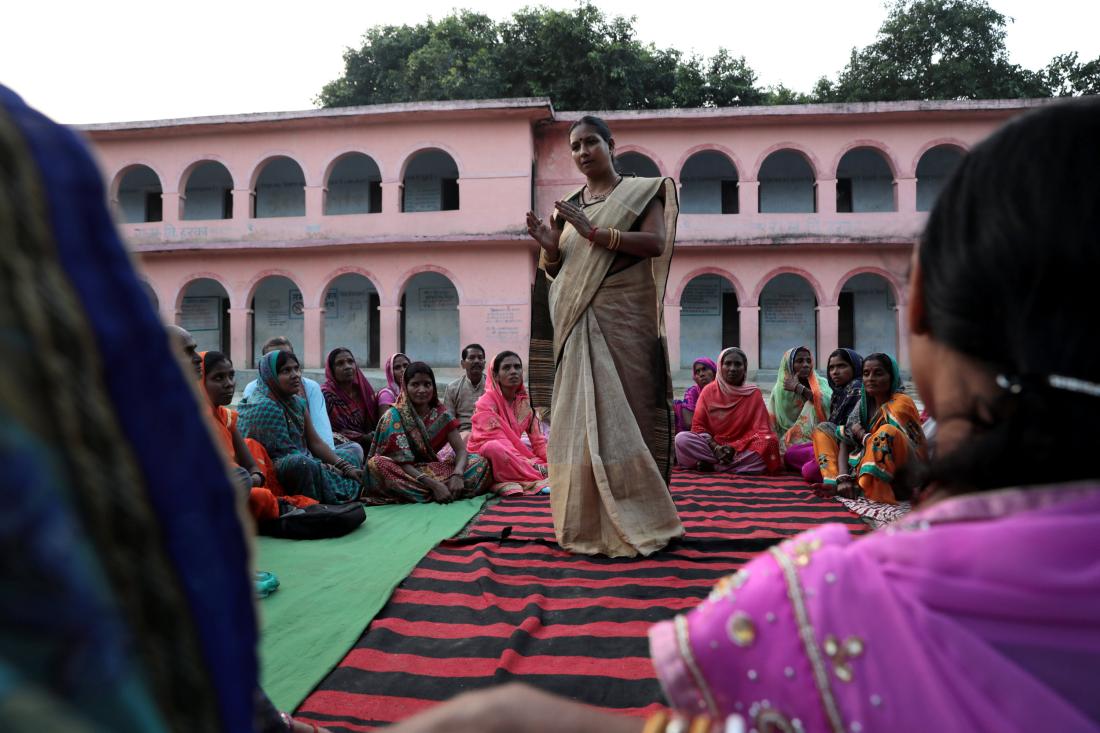 A group of women sitting around another woman speaking as part of business training in India