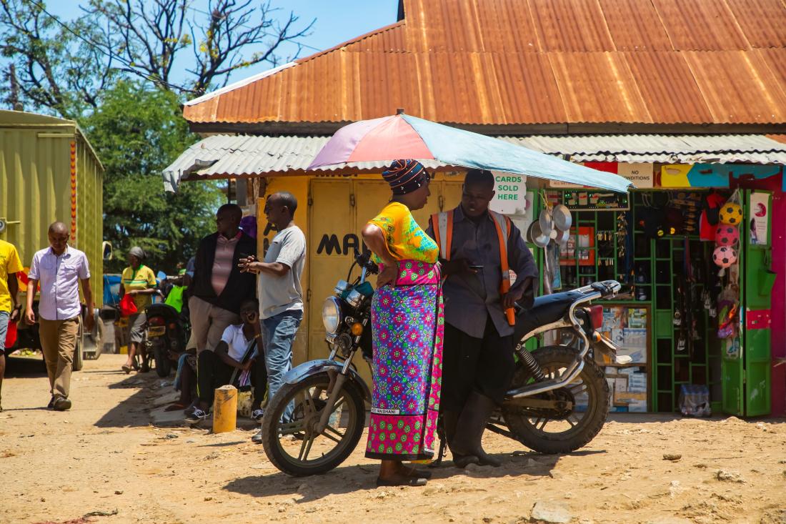 Woman and man talk outside of shops in Kenya, J-PAL Africa evaluation summary
