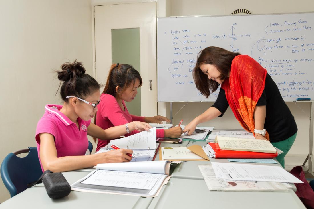 Three women doing paperwork and and making financial decisions together in the Philippines