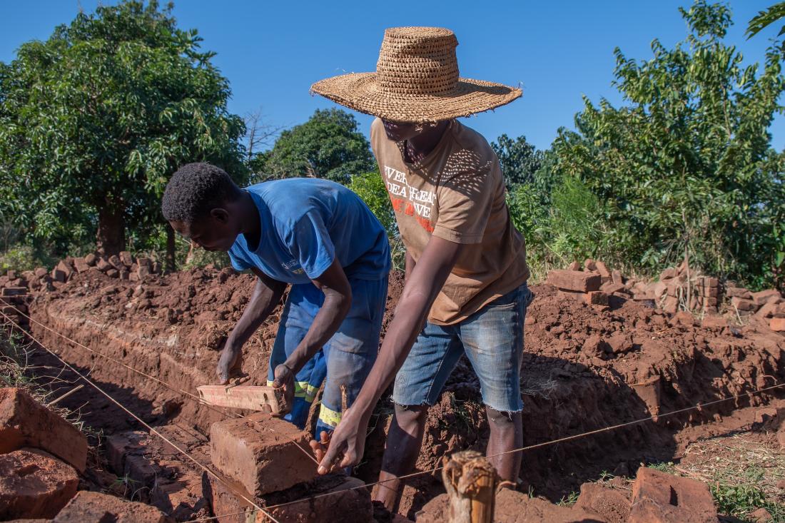 Young farmers construct an exterior wall of a home in Malawi, J-PAL Africa evaluation summary