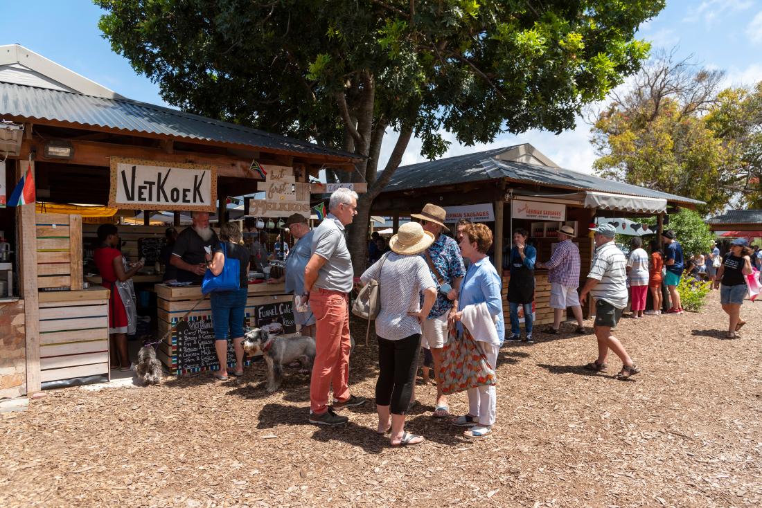 Two women and two men talking near a crowded market place