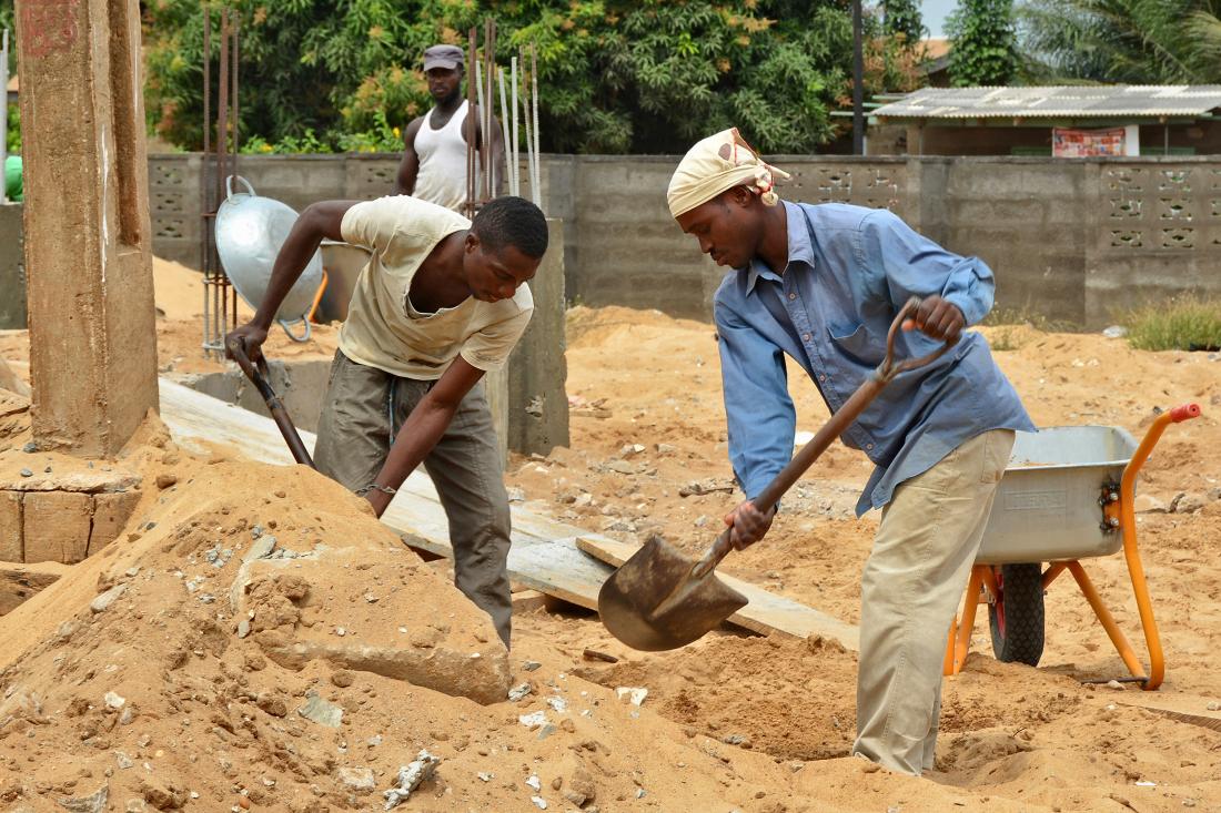 Two construction workers shoveling dirt.