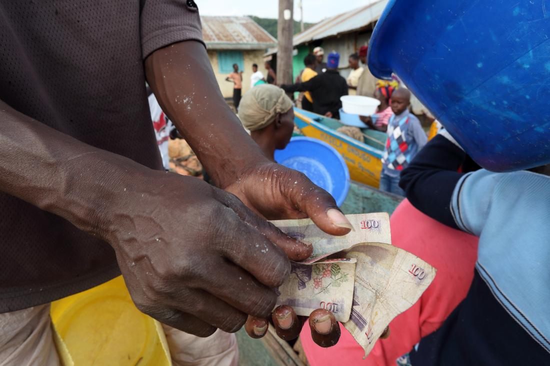 A street vendor counting money in Kenya J-PAL Africa evaluation summary