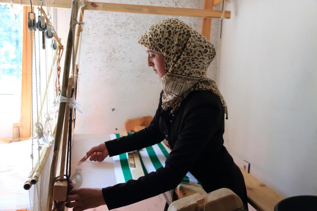 Woman with headscarf works on loom in textiles shops in rural Morocco