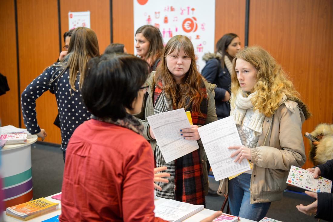 Two young jobseekers talking to an person at a job fair in France