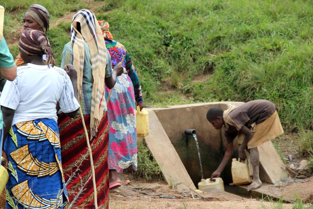 A boy collects drinking water from a well in Rwanda. 